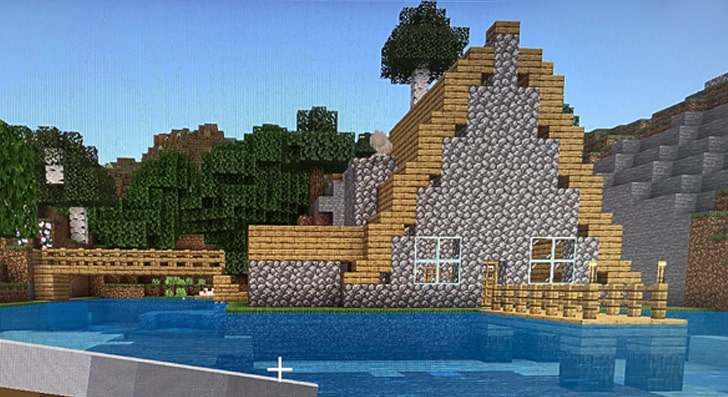 A lakeside cabin in Minecraft with a wooden A-shaped roof and a little jetty.