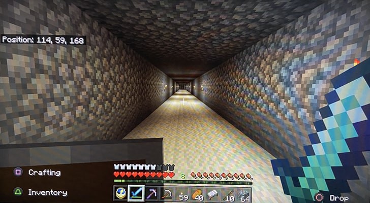 Looking down a long tunnel in Minecraft, with torches lighting up the passageway.